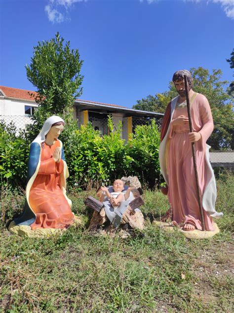 Foto di un presepe da esterno ben illuminato e integrato nel paesaggio del giardino