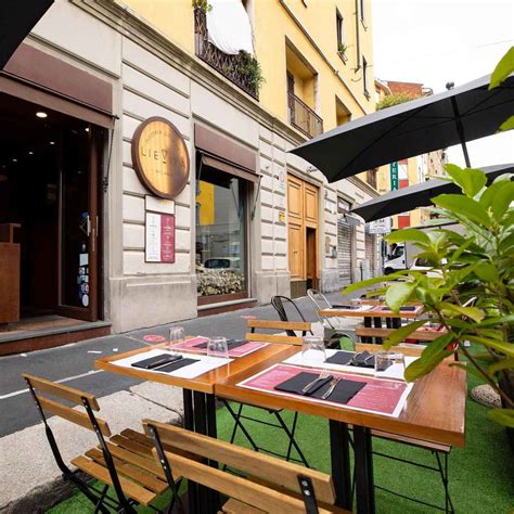 Foto dell'area esterna di una pizzeria con tavoli e piante, ideale per cene all'aperto