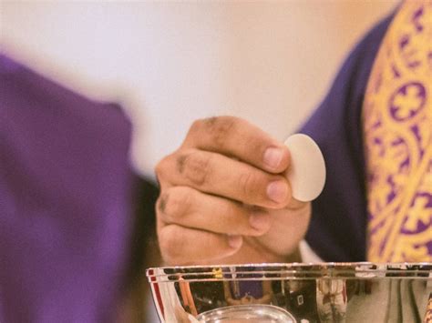 Sacerdote che offre la comunione ai fedeli, con enfasi sulla ricezione in mano