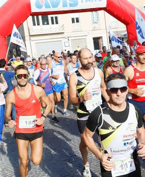 Corridori in azione durante un trofeo podistico serale nel centro storico di un paese illuminato a festa