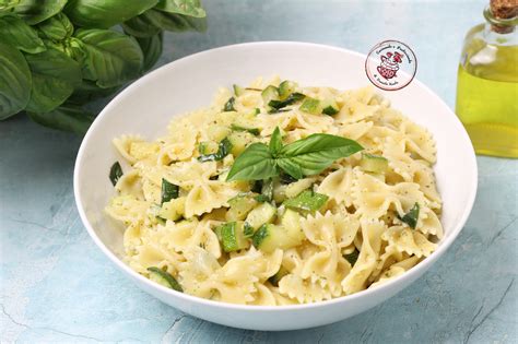 Foto di pasta con zucchine e basilico in un piatto, con foglie fresche di basilico e spicchi di limone.