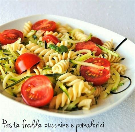 Ciotola di pasta fredda con zucchine e basilico, con decorazione di foglie di basilico.