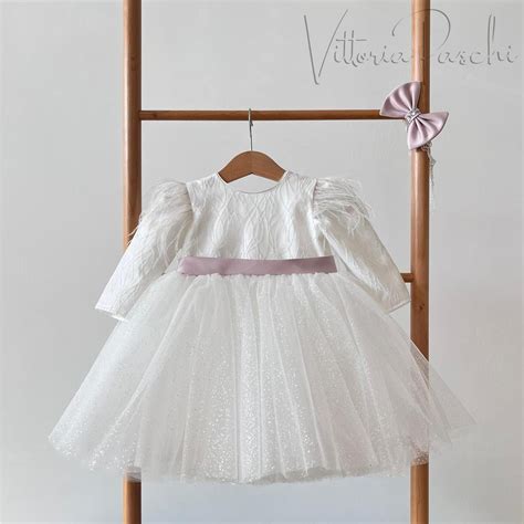 Bambina con vestitino da battesimo e maglioncino