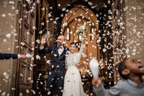 Coppia di sposi felici che escono da una chiesa, con amici che lanciano riso o petali