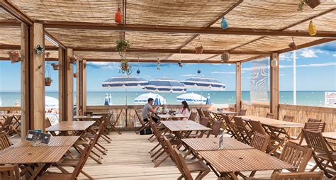 Foto dello spazio bar con tavolini vista mare e atmosfera rilassata
