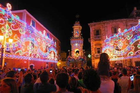 Foto panoramica di una festa religiosa in Puglia con folla e luminarie