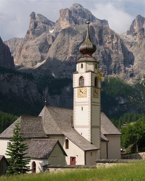 Veduta panoramica della Chiesa di San Vigilio a Colfosco con il Massiccio del Sella sullo sfondo