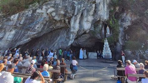 Foto di gruppo di pellegrini e volontari Unitalsi davanti alla Grotta di Lourdes durante una celebrazione