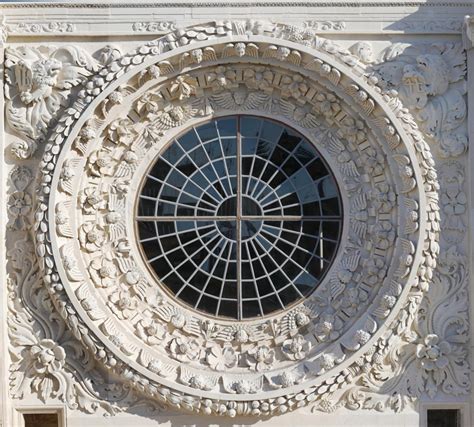 Dettaglio del rosone centrale della facciata con le insegne nobiliari e i fregi in pietra leccese.