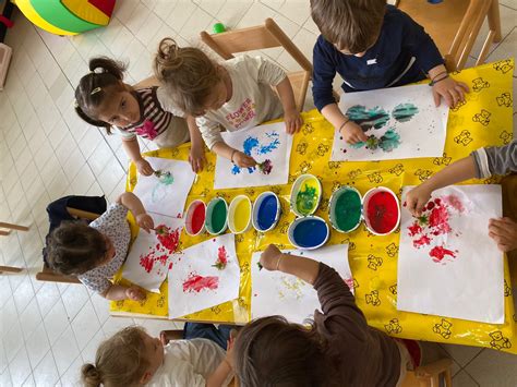 bambini che decorano piccoli vasi di terracotta in un laboratorio creativo