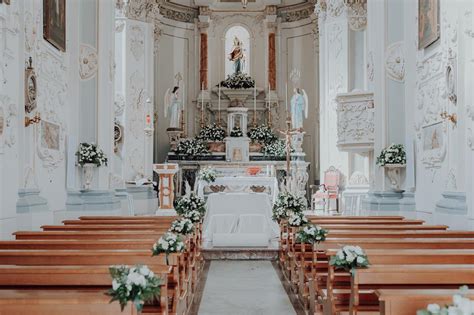 Interno di una chiesa addobbata per matrimonio con fiori lungo la navata e sull'altare