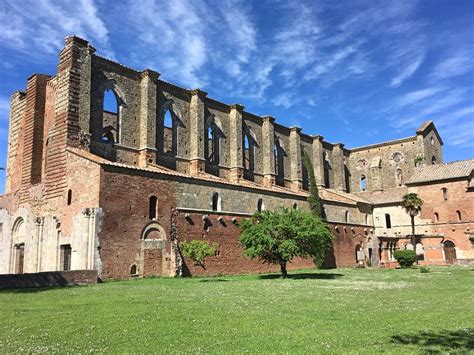Interno dell'Abbazia di San Galgano con il cielo come tetto e l'erba sul pavimento