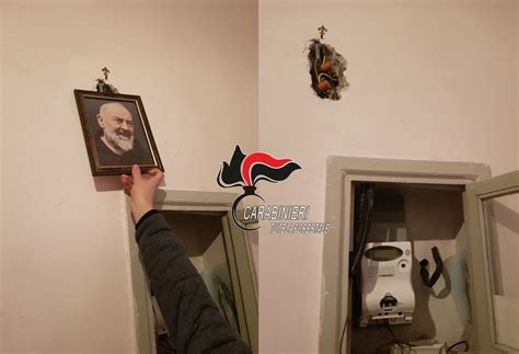 Foto di un quadro di Padre Pio che copre un allaccio abusivo all'impianto elettrico
