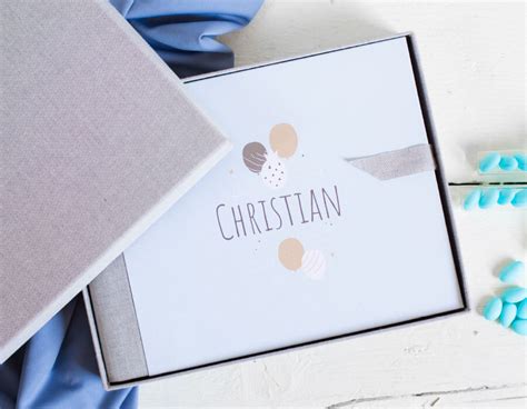 Galleria di immagini che mostrano diversi tipi di packaging per album battesimo: cofanetto in tessuto, custodia in legno, box magnetico.