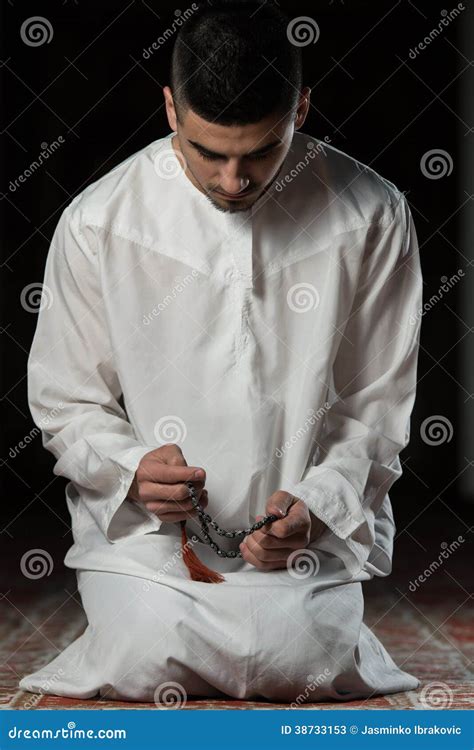 Uomo musulmano in abito tradizionale mentre prega in una moschea