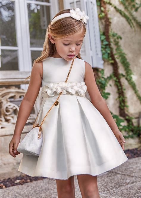 Foto di una bambina di 12 anni in un elegante abito da cresima, con uno sfondo luminoso e festivo