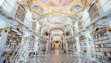 Interno della biblioteca barocca di Admont con librerie dorate e affreschi sul soffitto