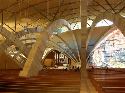 Interno del Santuario di Padre Pio con vista sugli archi in pietra, l'altare di Arnaldo Pomodoro e la vetrata