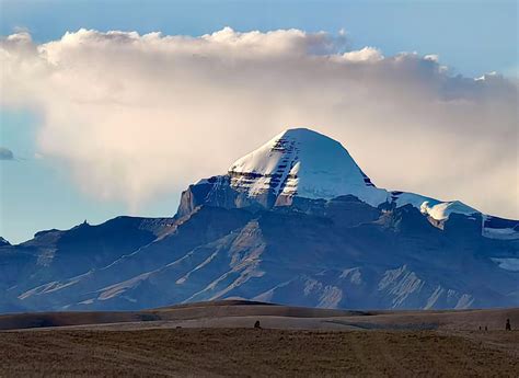 Vista panoramica del Monte Kailash in Tibet, con neve sulla cima e paesaggio circostante.