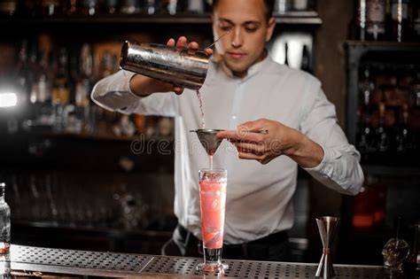 Immagine di un bartender che prepara un cocktail elaborato con ingredienti freschi in un bar di lusso.