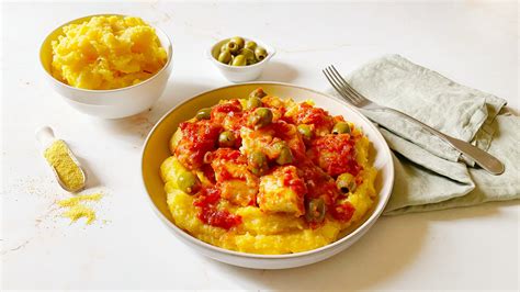 Tavola imbandita con diversi piatti a base di baccalà e polenta