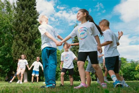 Bambini che giocano e fanno attività all'aperto durante un Grest estivo, con animatori in magliette colorate.