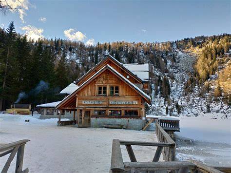 Lago Nambino ghiacciato e innevato con un caratteristico rifugio alpino