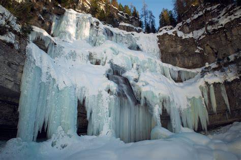 Cascata di Vallesinella ghiacciata e innevata in un bosco invernale