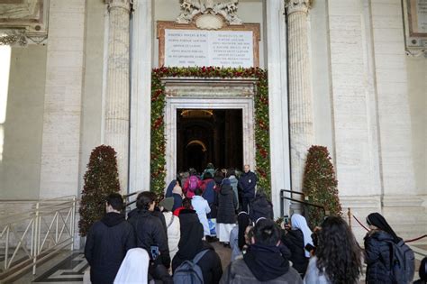 Foto di gruppo dei pellegrini LGBTQ+ durante il cammino verso la Porta Santa con simboli arcobaleno