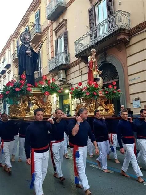 Scatto della processione solenne con i simulacri dei santi patroni tra la folla e le decorazioni urbane.