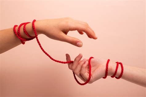 Mani di donne intrecciate con un filo rosso che parte dalla mano di una futura mamma