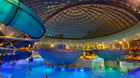 Piscine termali sotto una cupola di vetro con famiglie che giocano