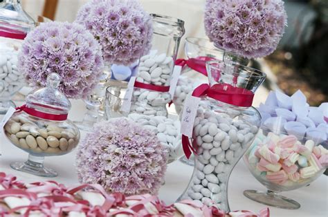 Esempio di allestimento per confettata con vasetti in vetro, nastri rossi e confetti di diverse sfumature