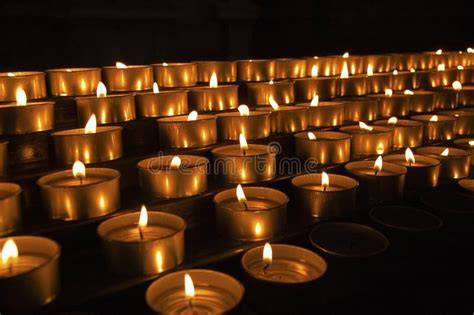 Foto di candele votive accese in una chiesa, che creano un'atmosfera di raccoglimento e spiritualità.