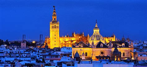 Veduta notturna della facciata della Cattedrale di Siviglia illuminata con la Giralda sullo sfondo