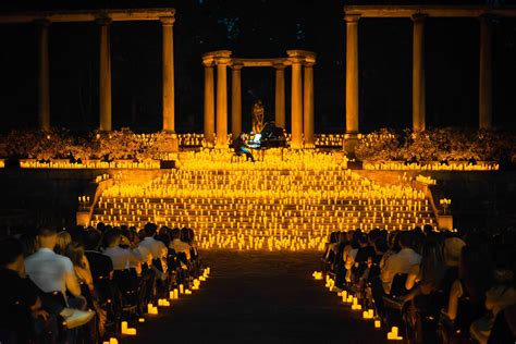 Fotografia di una processione notturna a Lourdes con migliaia di candele accese e pellegrini in preghiera