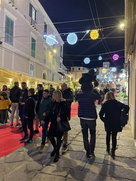 Foto di un borgo illuminato a festa con gente che passeggia tra stand gastronomici