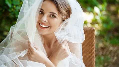 Sposa pensierosa in abito da sposa, seduta, con velo