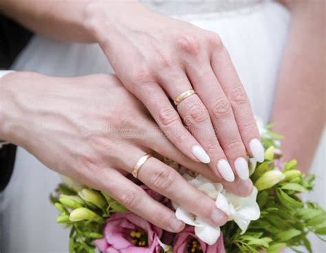 Mano di sposa con anello, sullo sfondo un bouquet