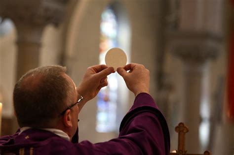 Sacerdote che eleva il calice e la patena durante la consacrazione eucaristica