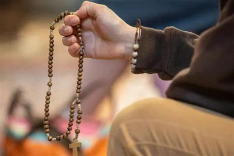 Immagine di una mano che tiene un rosario con uno sfondo notturno sereno