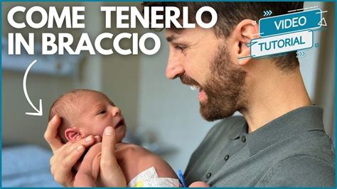 Foto di un neonato in braccio a un adulto con un piccolo gioiello