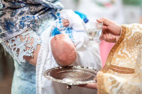 Foto di un bambino durante la cerimonia del Battesimo, immerso nell'acqua santa
