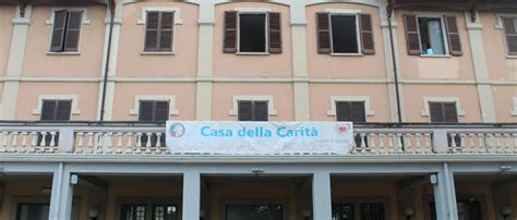 Esterno della Casa della Carità di Pavia, con un'insegna che ne indica la funzione di accoglienza.