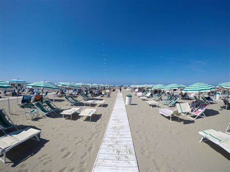 Ampia spiaggia dorata di Marina di Pietrasanta con ombrelloni e mare calmo