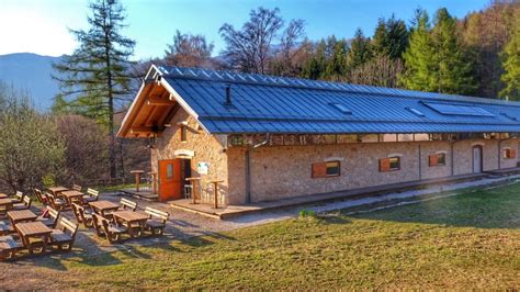 Famiglia che gioca sull'ampio prato di Malga Cimana con altalene