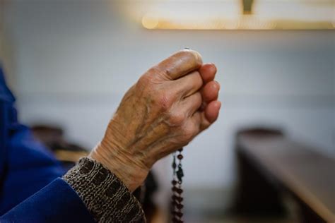 illustrazione di una nonna anziana che prega con un rosario, lacrime agli occhi