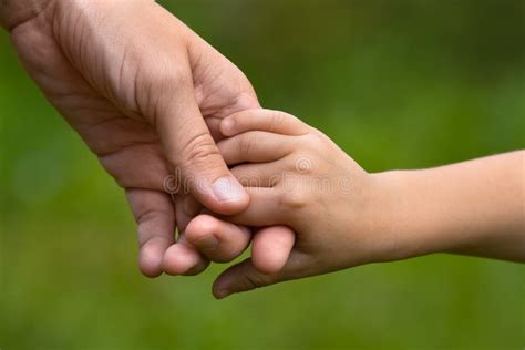 mano adulta che tiene dolcemente la mano di un bambino, simbolo di protezione divina
