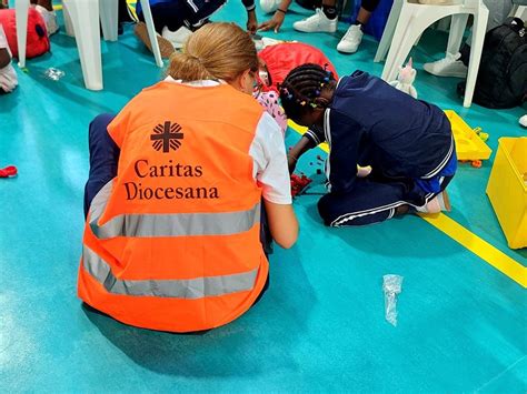 Volontari della Caritas che smistano donazioni alimentari e prodotti per l'igiene in un centro di raccolta.