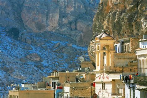 Vista aerea della città di Maaloula in Siria, con case scavate nella roccia e una chiesa cristiana evidente.